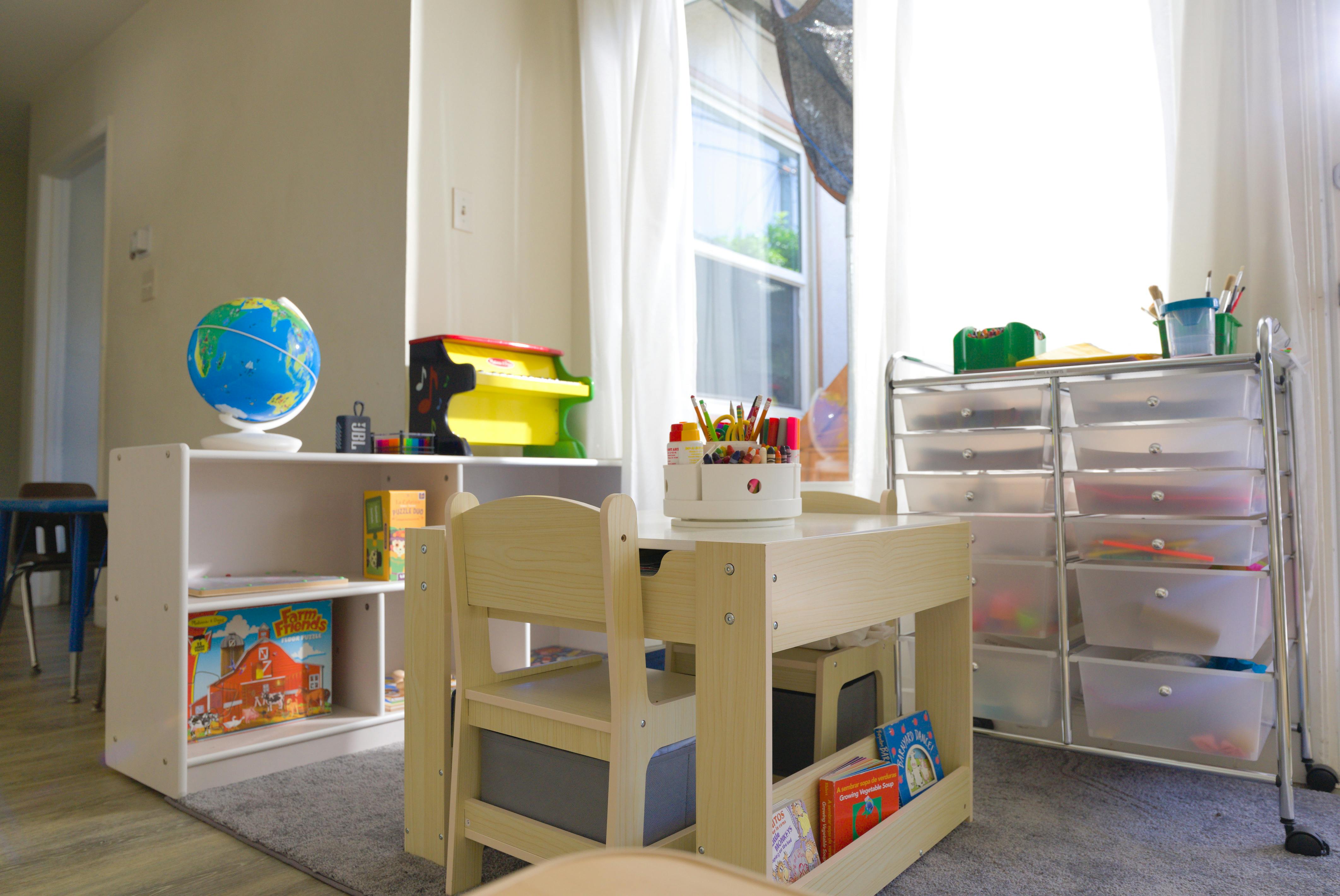 Children's play area with a small table, chairs, toy shelf, and art supplies