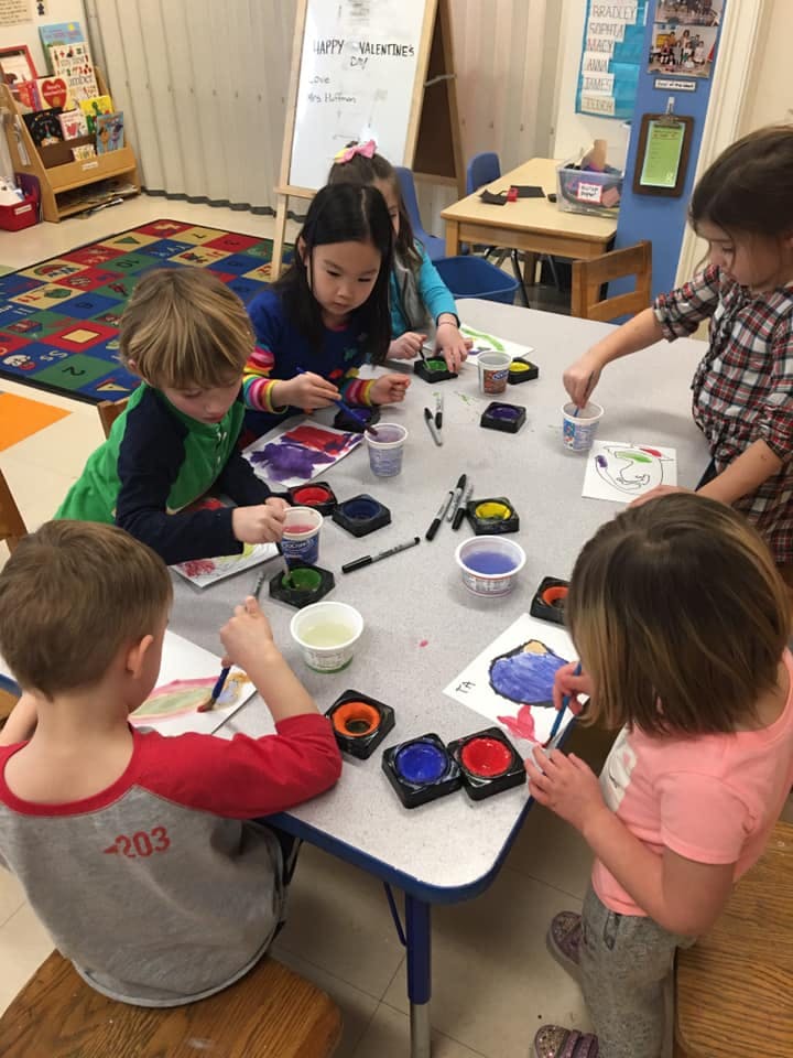 Children painting at a table in a classroom