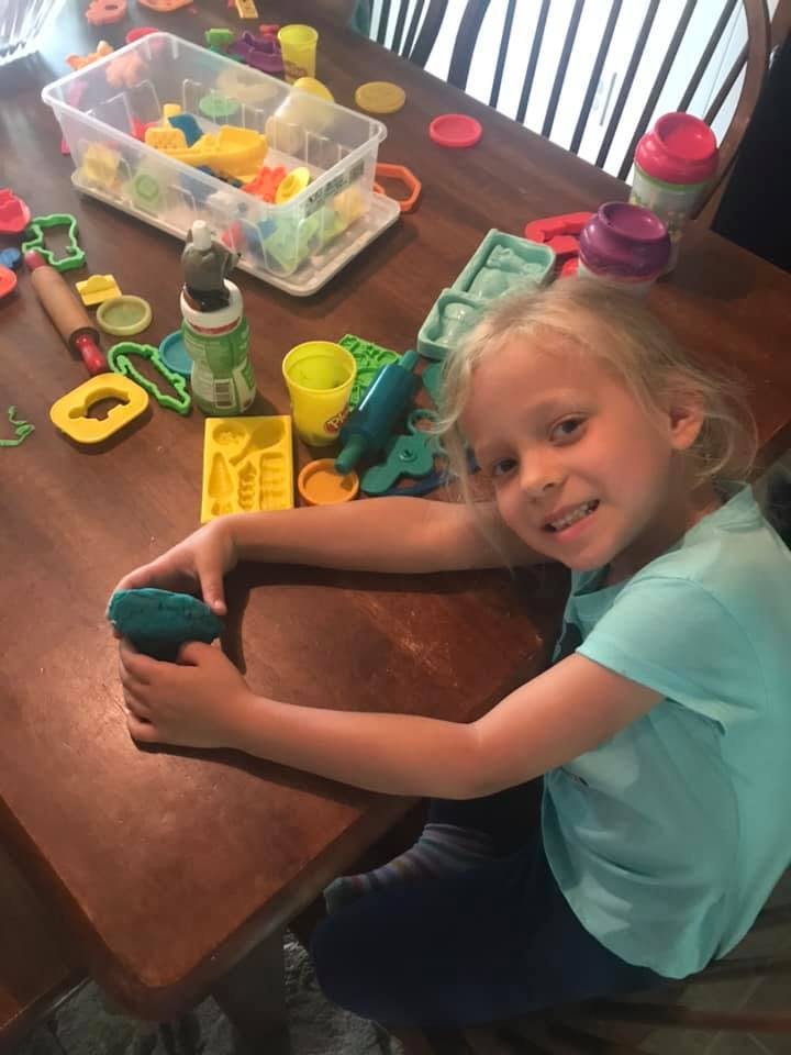 Child playing with modeling clay at a table