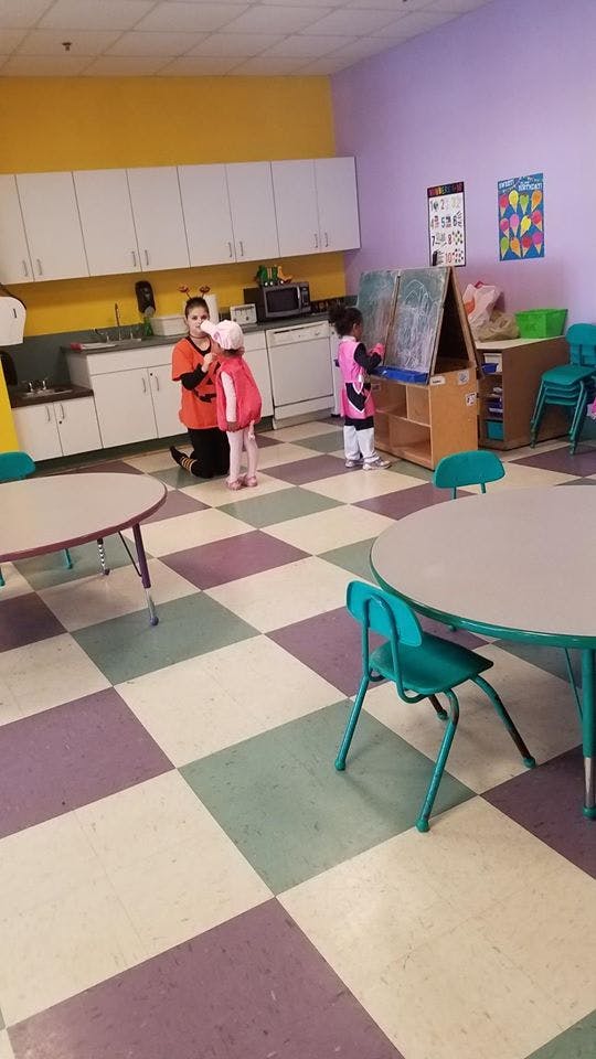Adult kneeling to speak with a child in a classroom