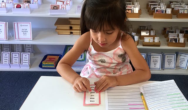 Child working with learning cards at a table in a classroom