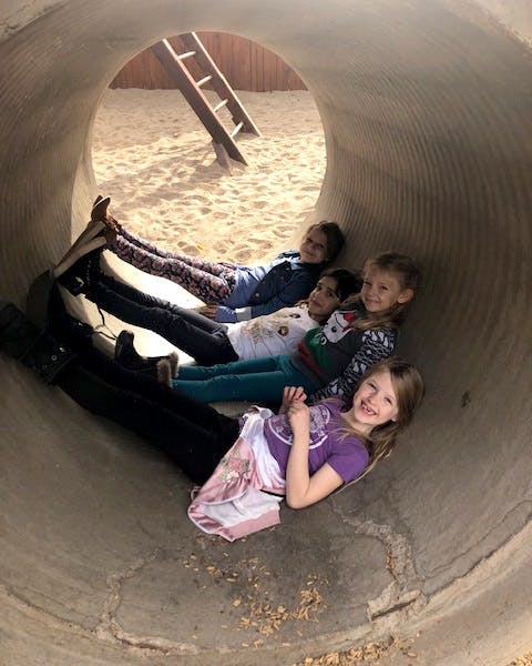 Four children lying inside a large concrete tunnel