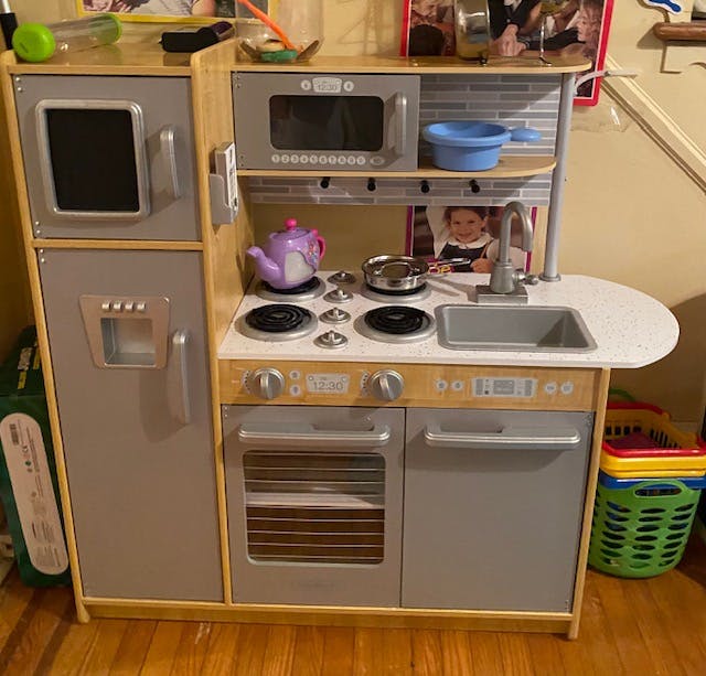 Child's play kitchen with stove, sink, microwave, and refrigerator