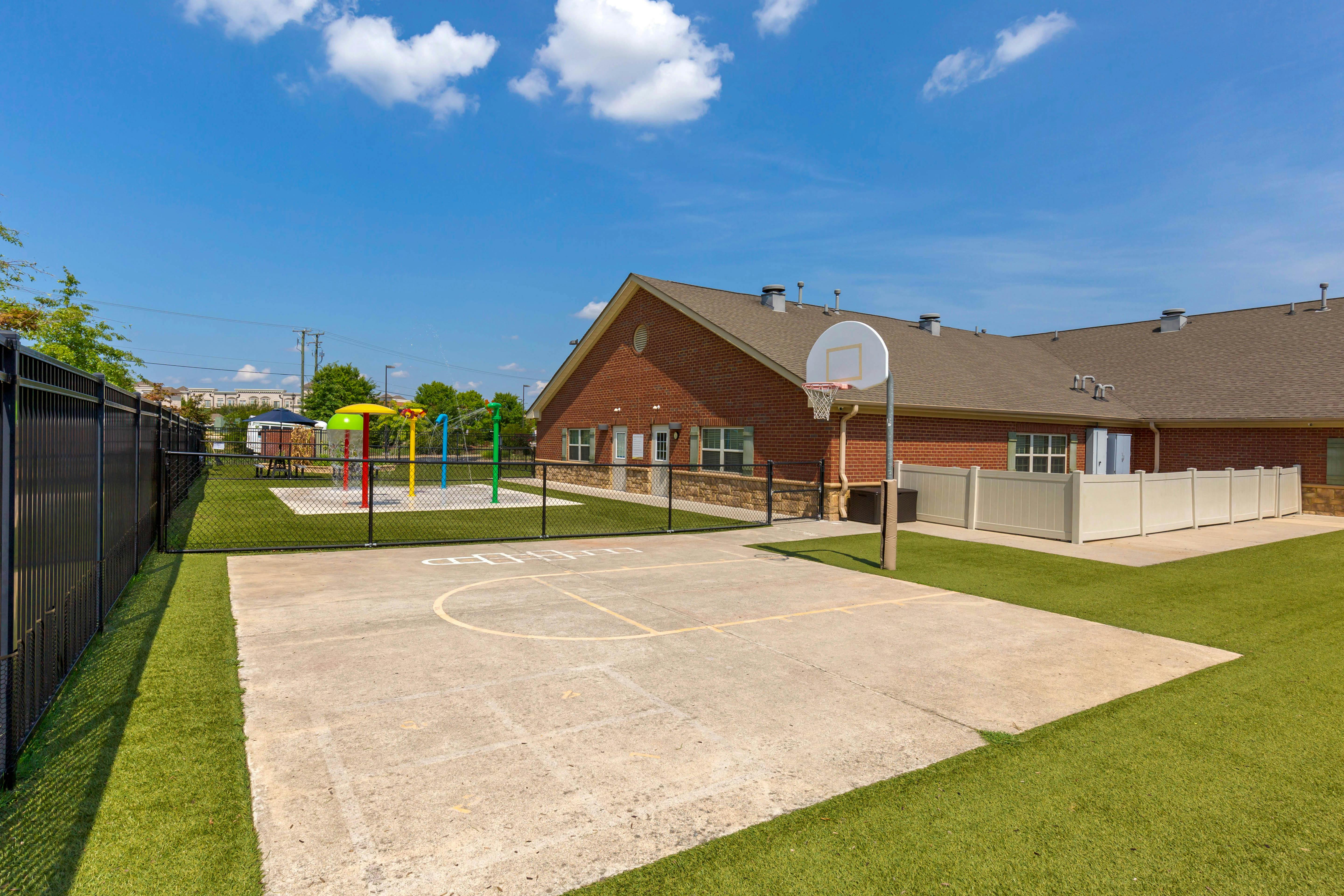 Outdoor children's play area with a water park, basketball court, and turf grass
