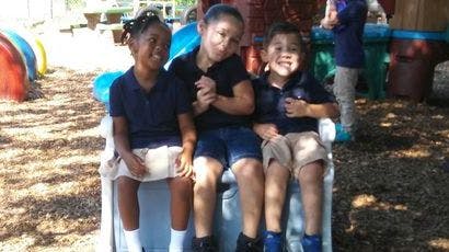 Three children sitting together on a playground