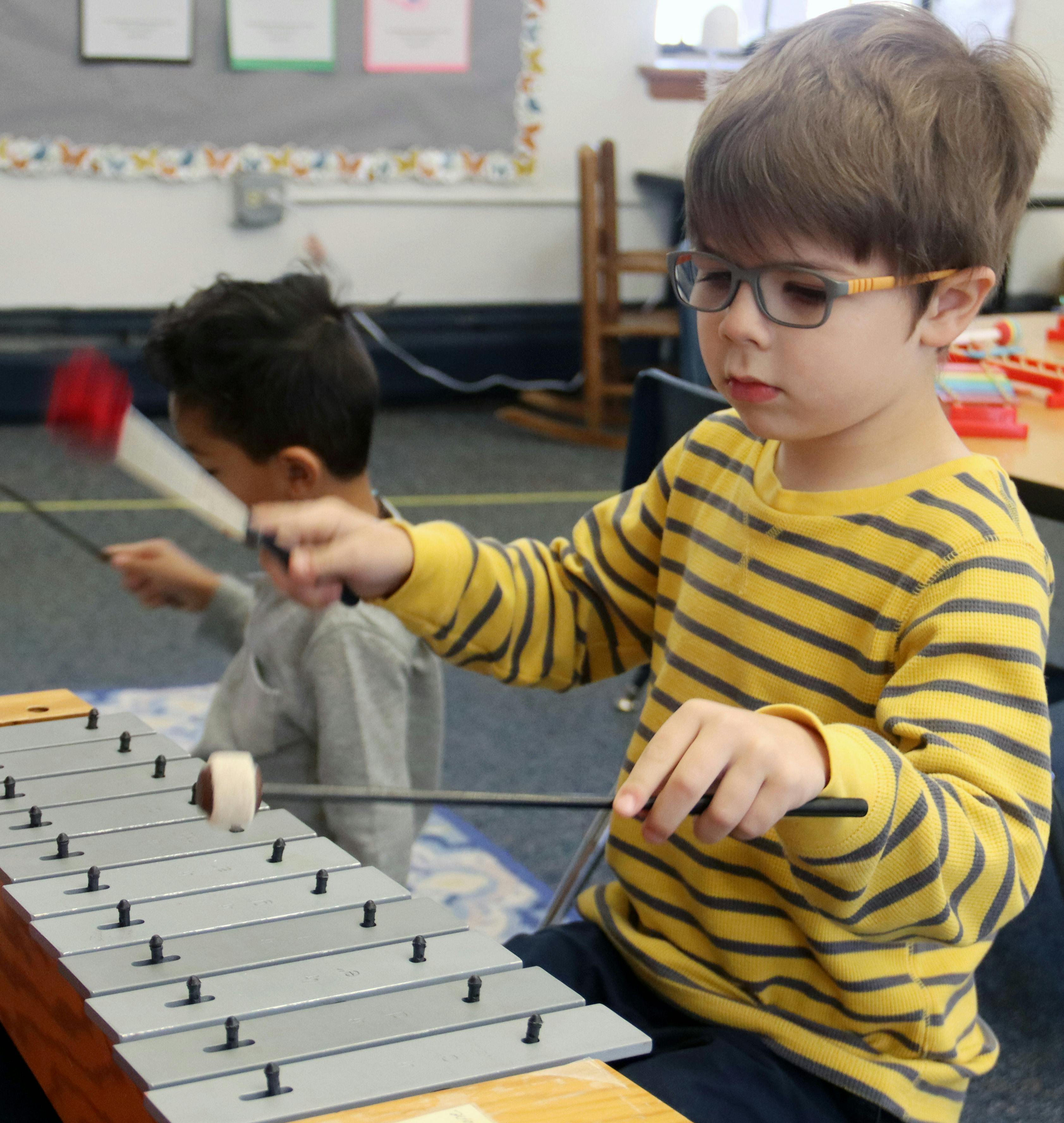 Child playing a xylophone in a classroom