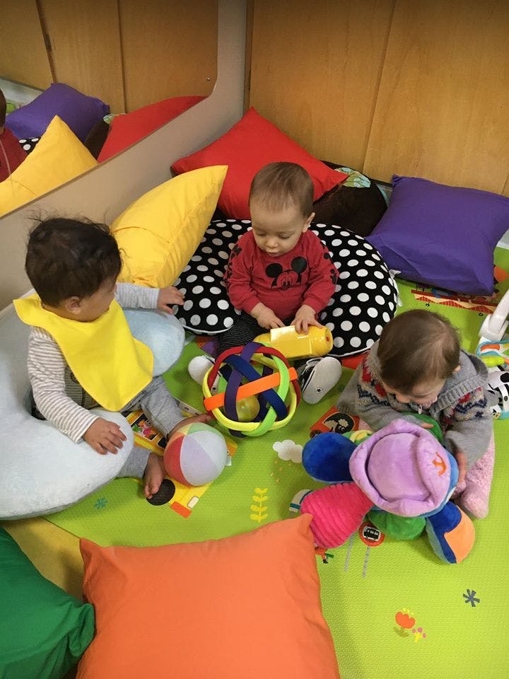 Three children playing with toys on a green mat