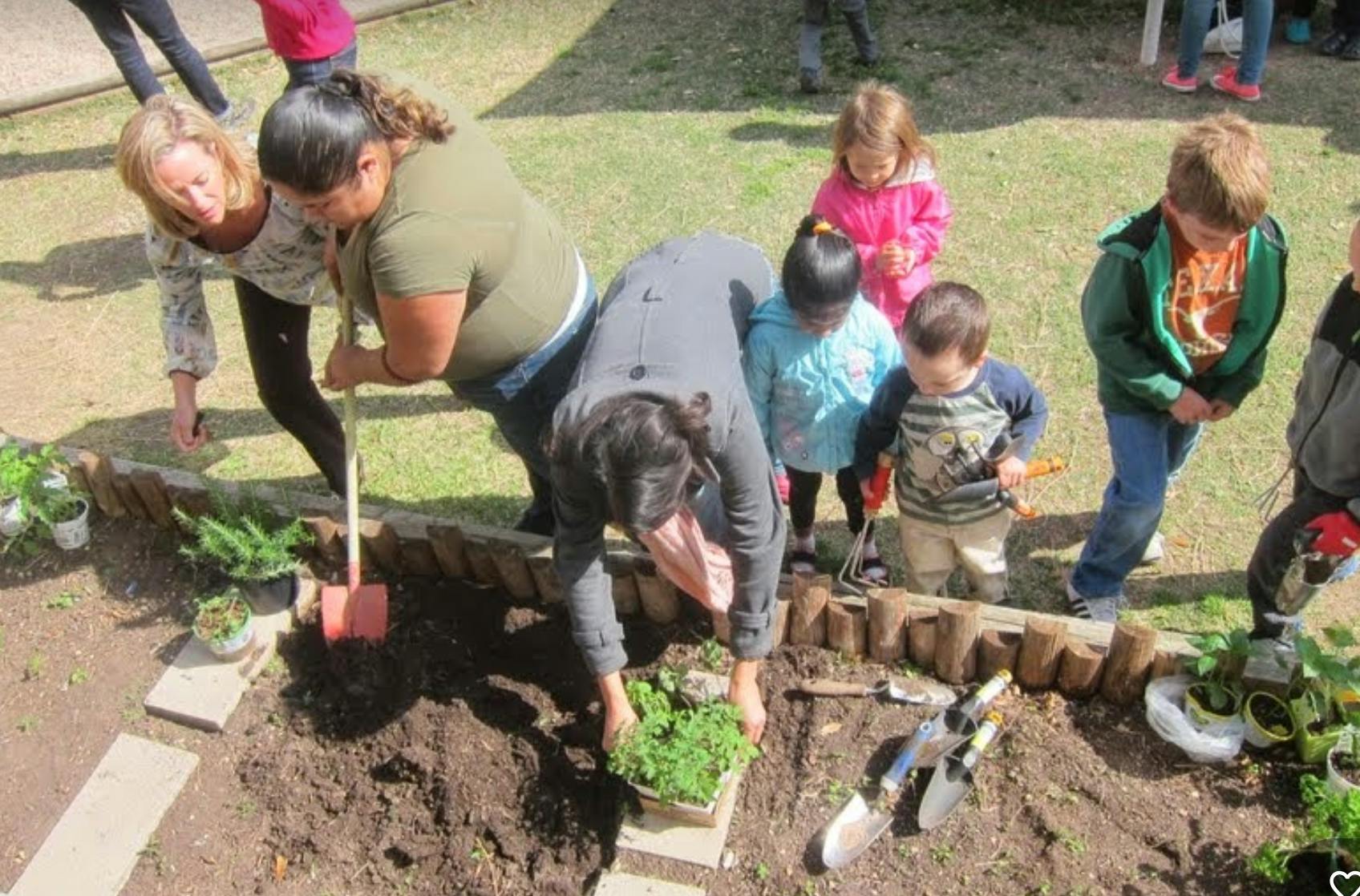 People and children planting in a garden bed