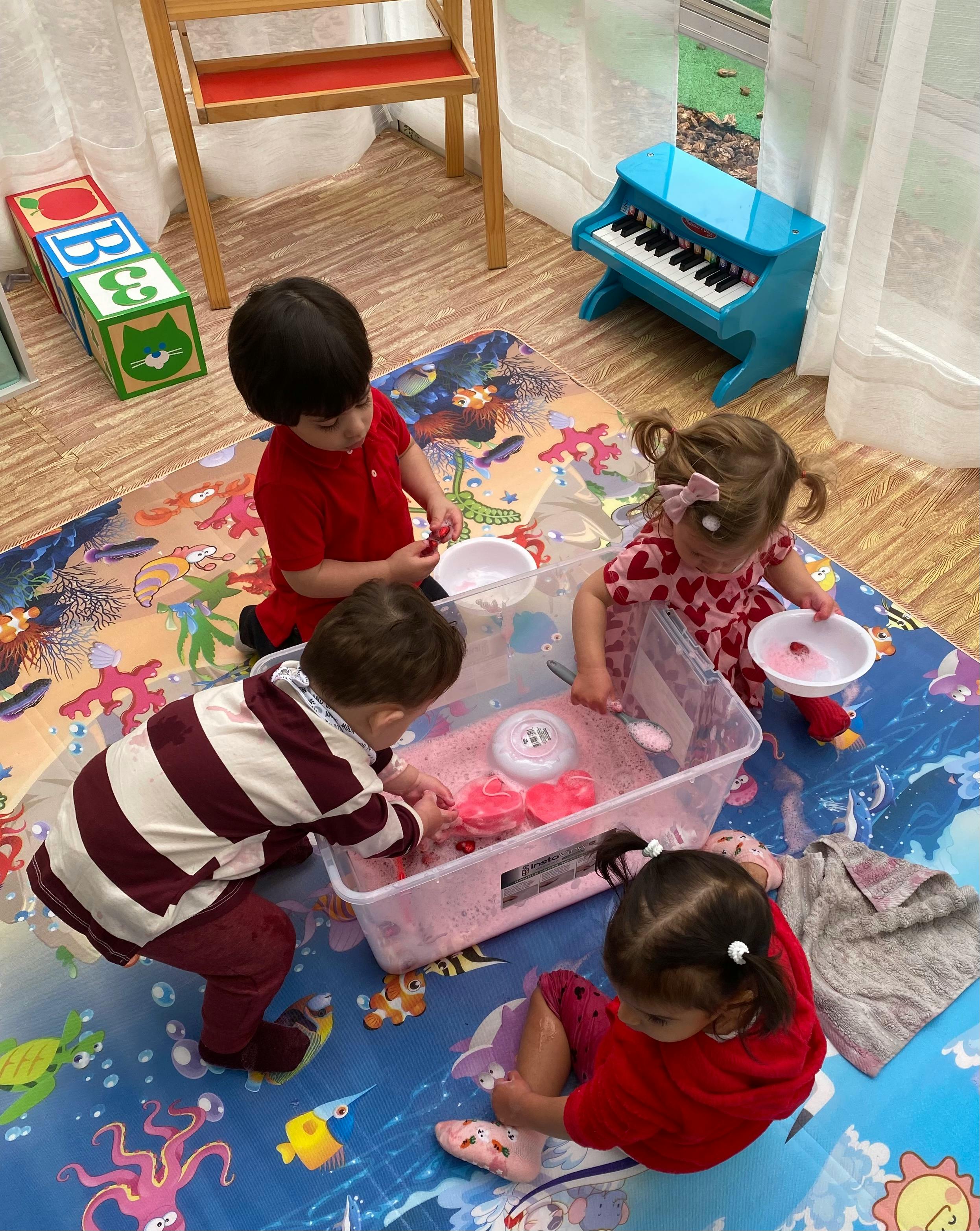 Four children playing with a sensory bin on a colorful mat