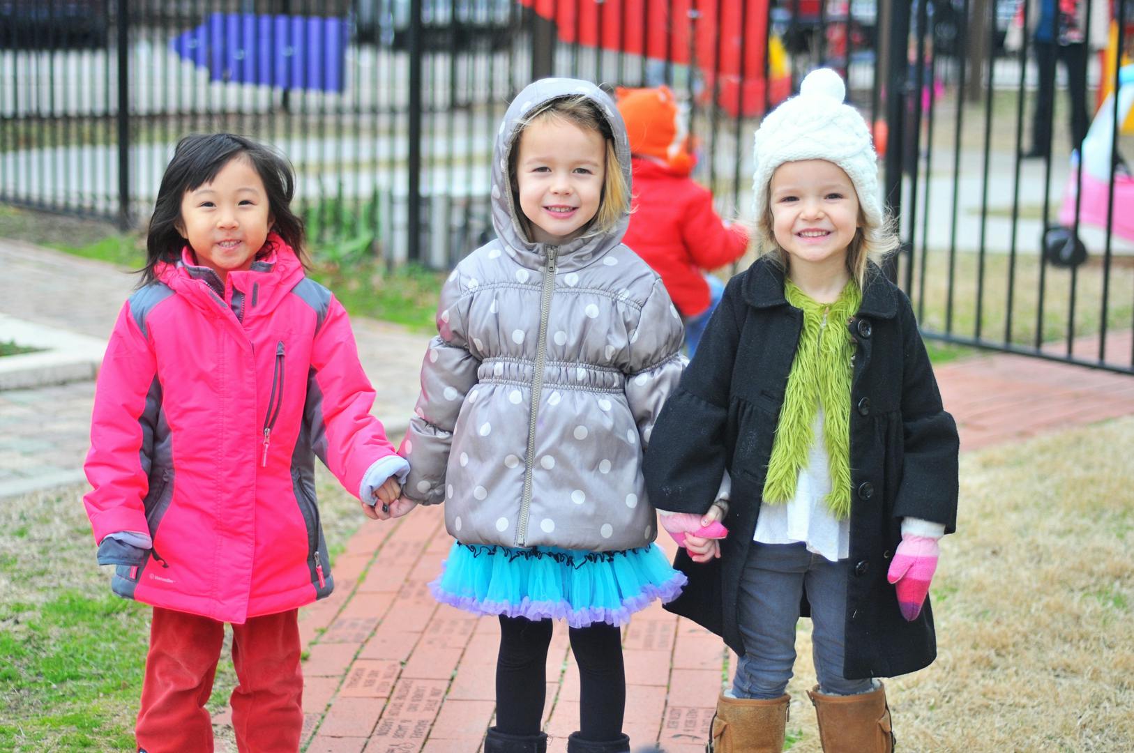 Three children holding hands outdoors