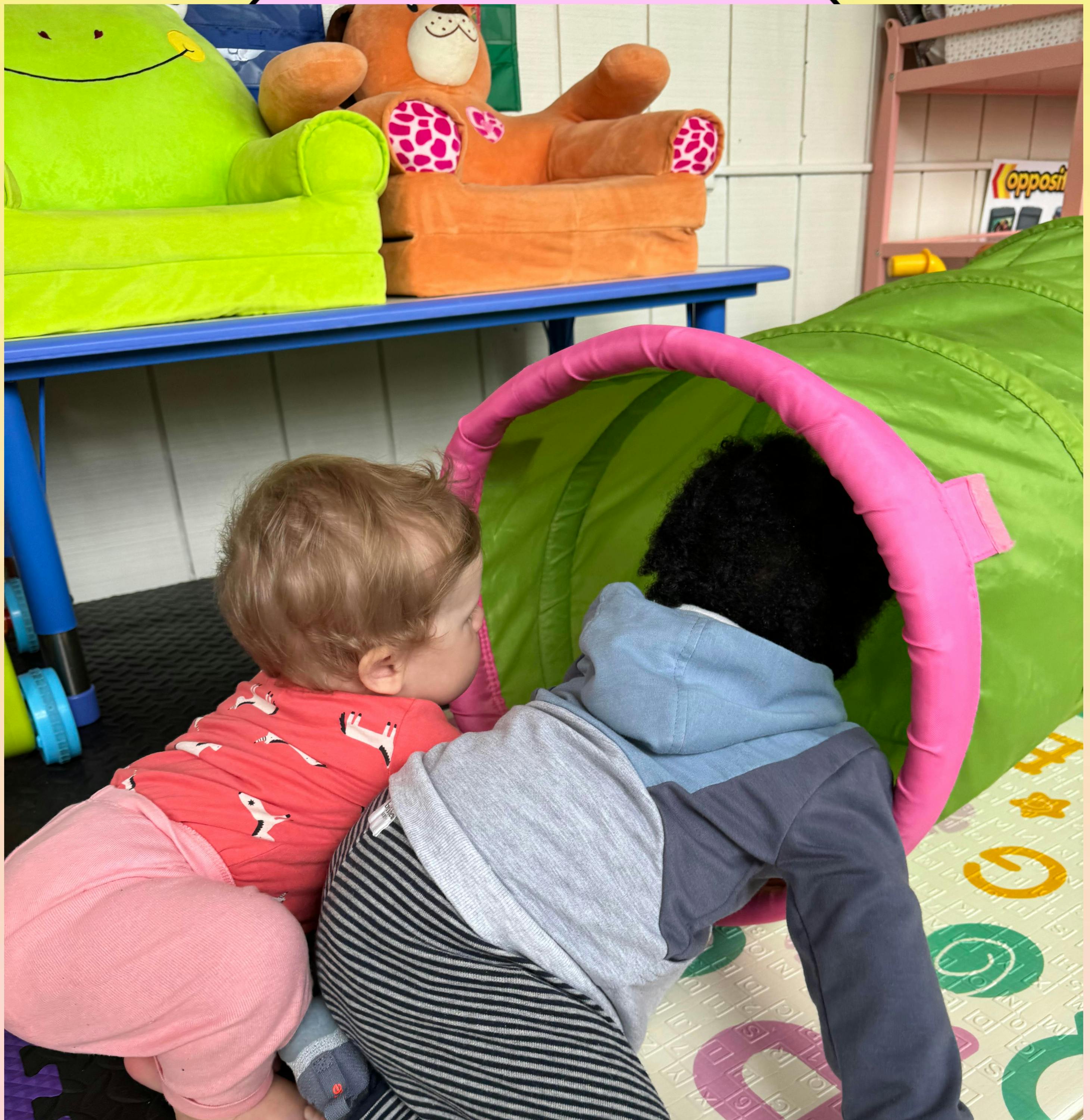Two children playing with a green and pink tunnel