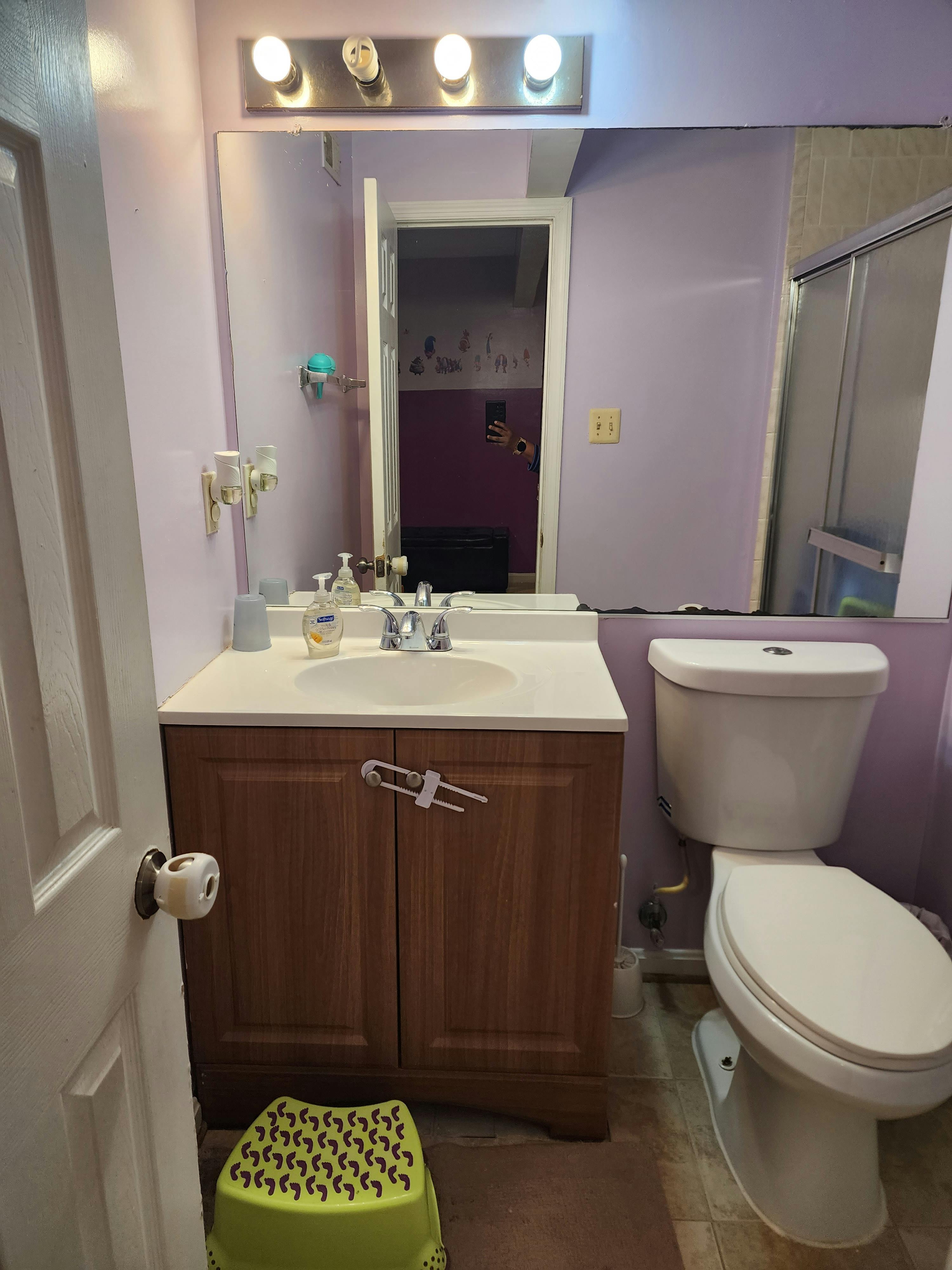 Bathroom with a vanity, sink, mirror, and toilet