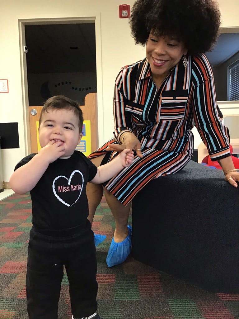 Person sitting and child standing, holding hands