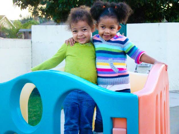Two children standing on a colorful play structure
