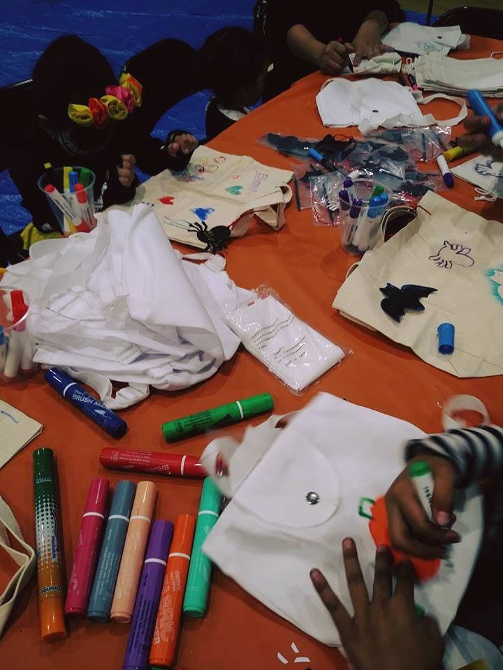 People decorating bags and shirts with markers and fabric cutouts