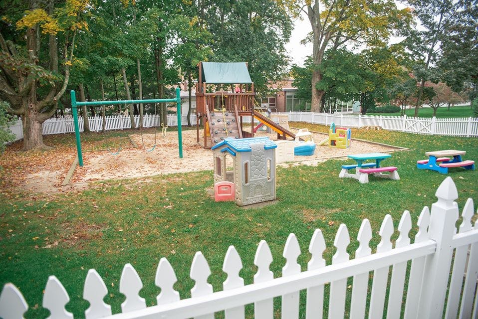 Playground with swings, slide, playhouse, and picnic tables