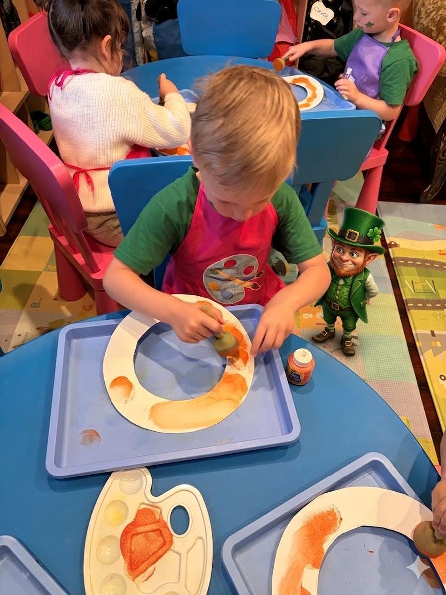 Child painting a large paper letter C orange at a blue table
