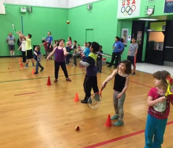 Children playing with rackets and balls in a gymnasium