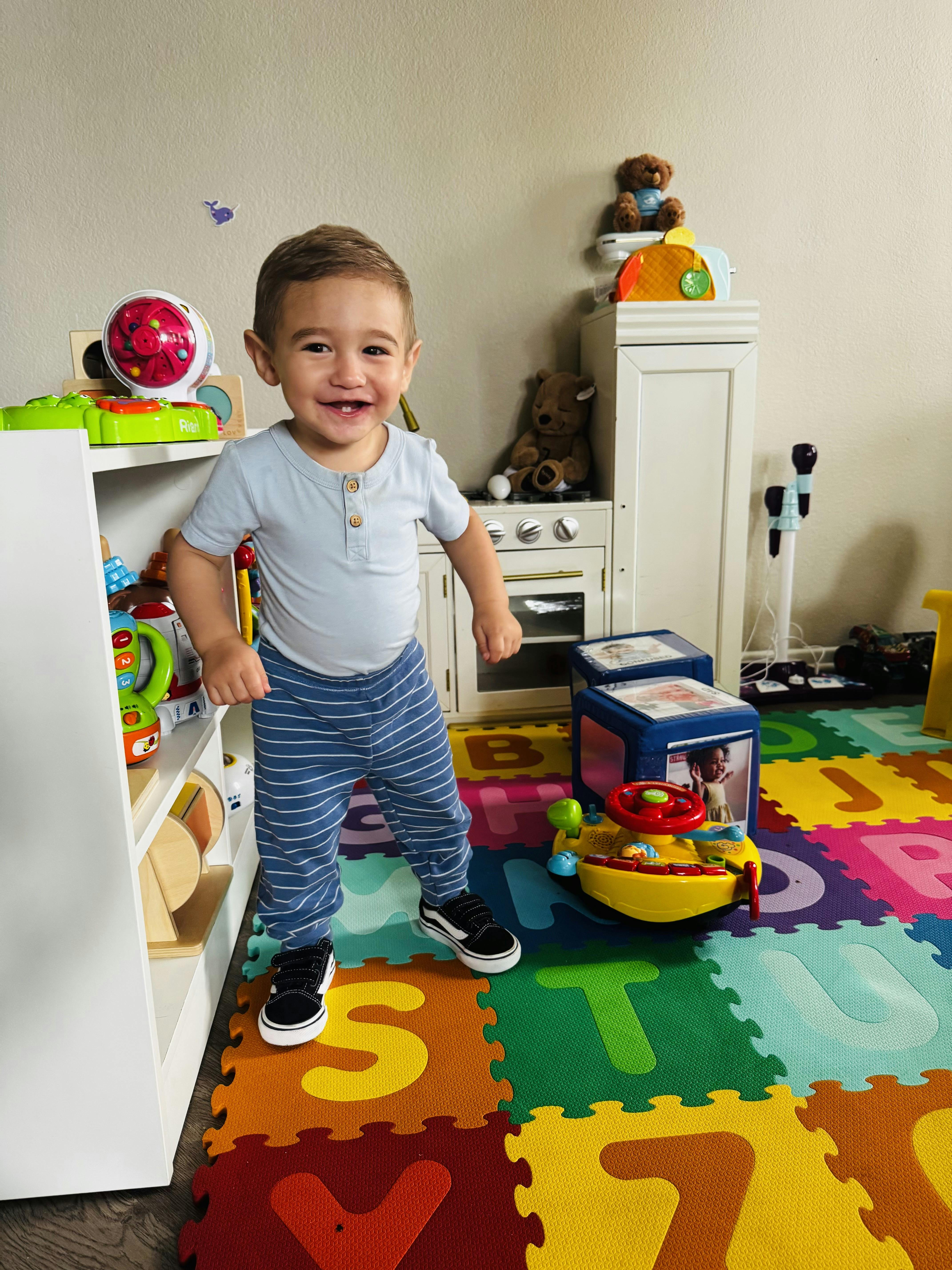 Child standing on a colorful alphabet play mat in a playroom
