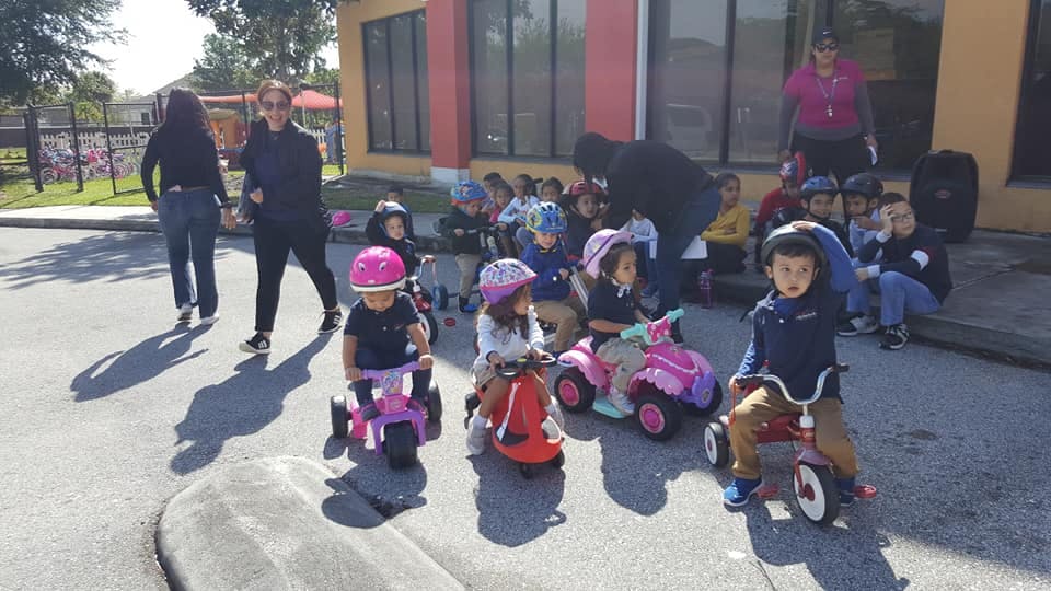Children on tricycles with adults nearby