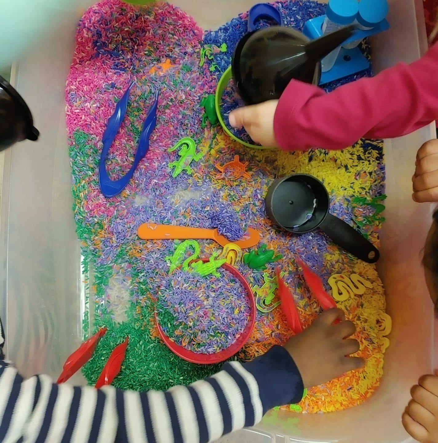 Children playing with colorful rice and sensory tools