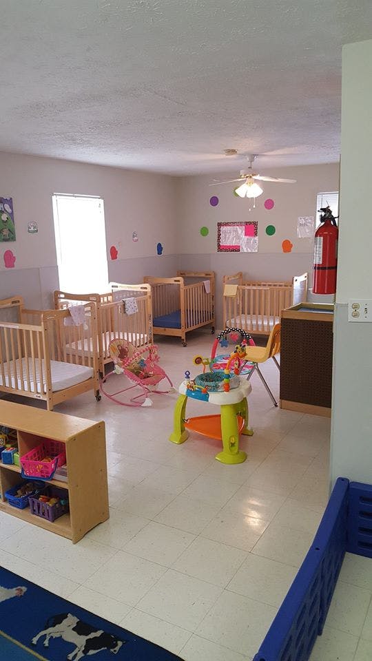 Nursery room with multiple cribs and infant play equipment