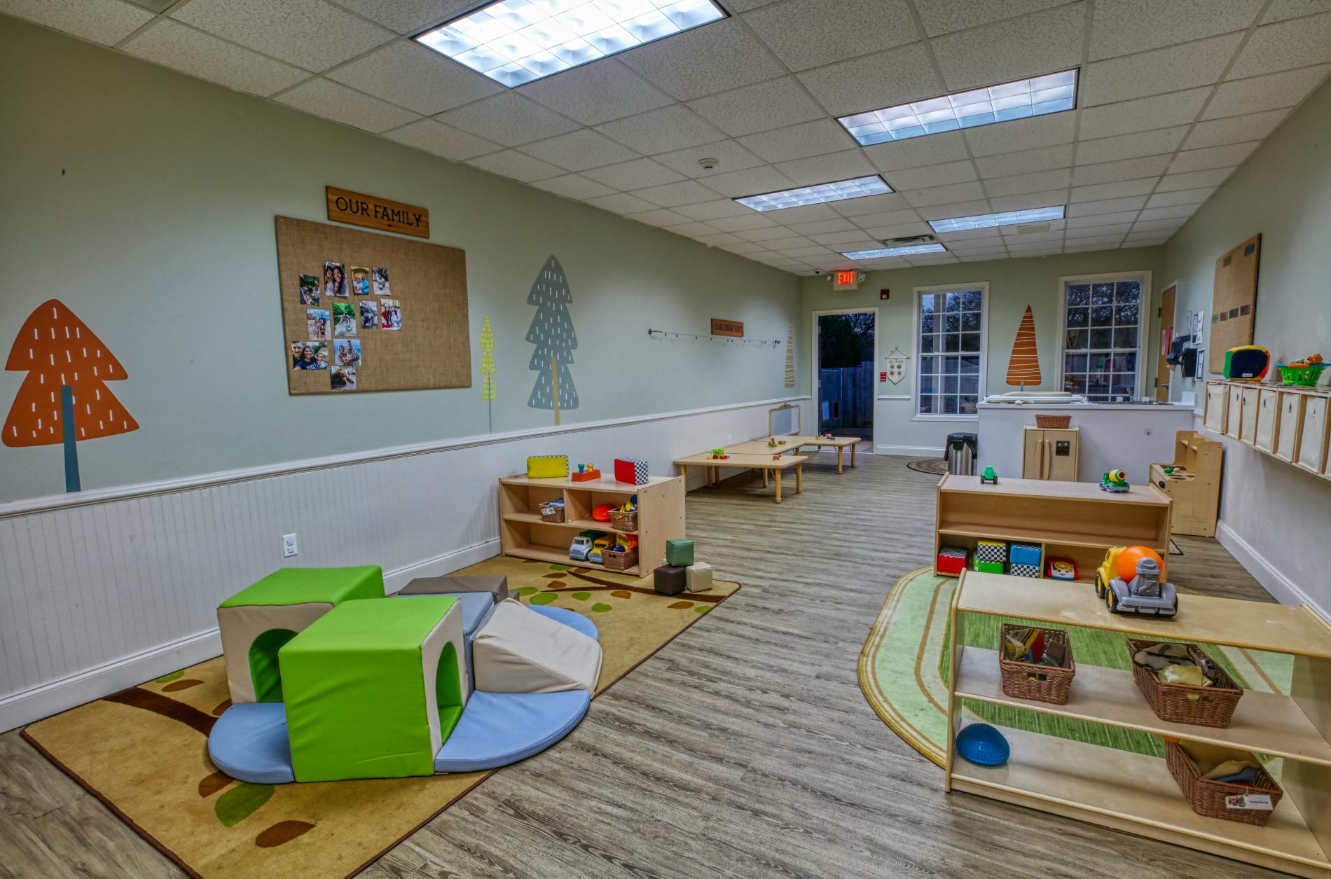 An empty early childhood classroom with play structures, tables, and toys
