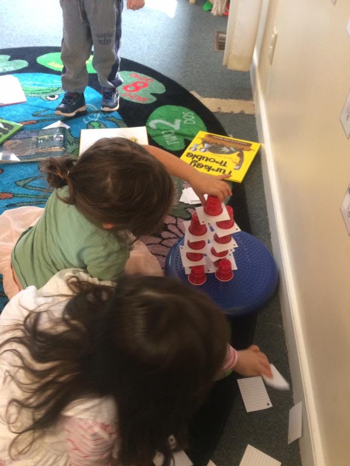 Two children playing with red cups and cards on the floor
