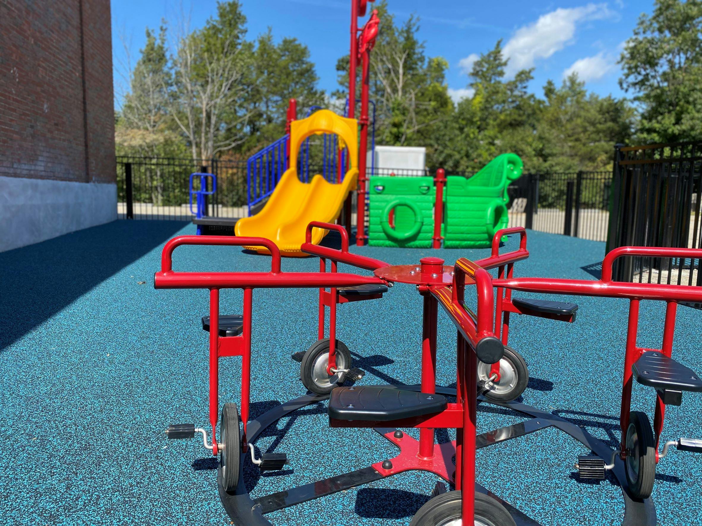 Red playground equipment on blue ground with yellow slide in background