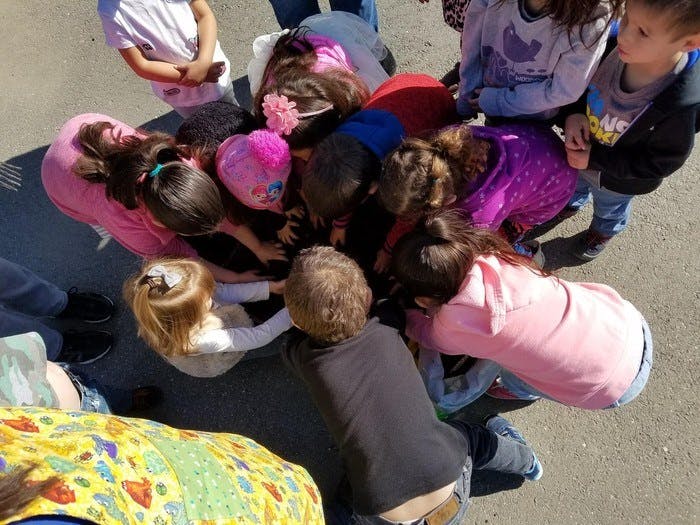 Group of children gathered around an object on the ground