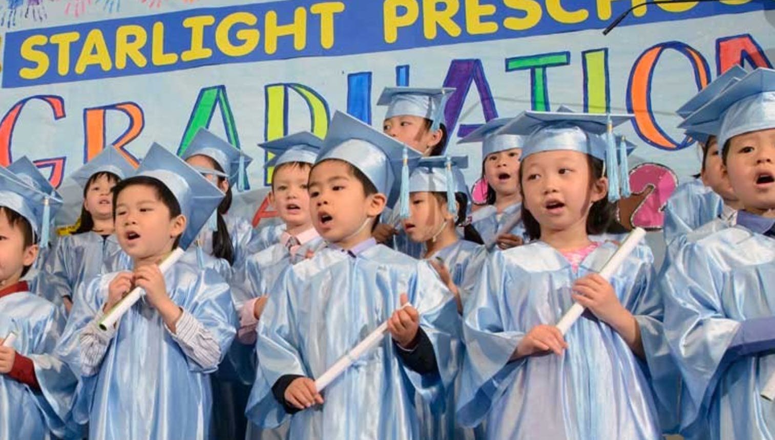 Children in graduation caps and gowns singing