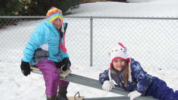 Two children on a seesaw in the snow