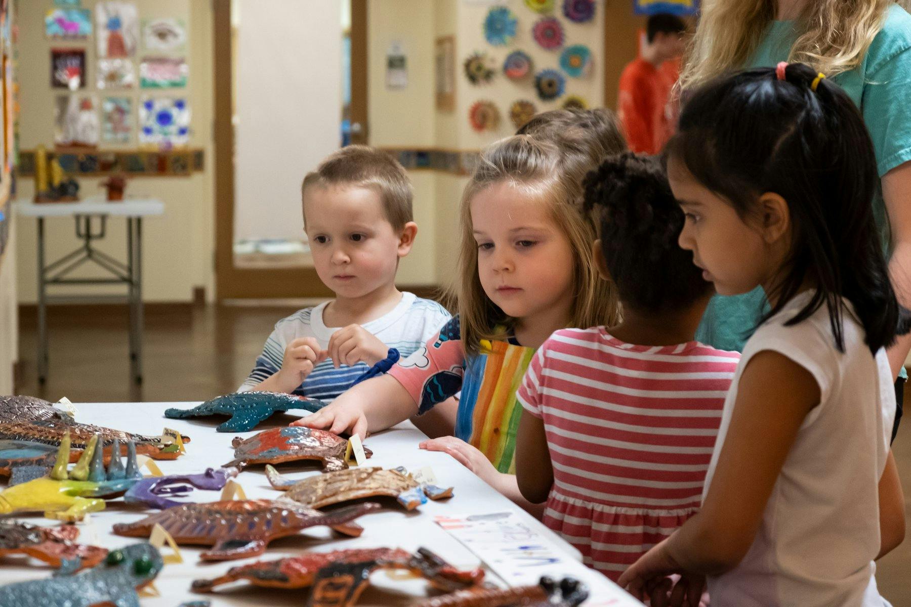 Children looking at toy animals on a table in a classroom