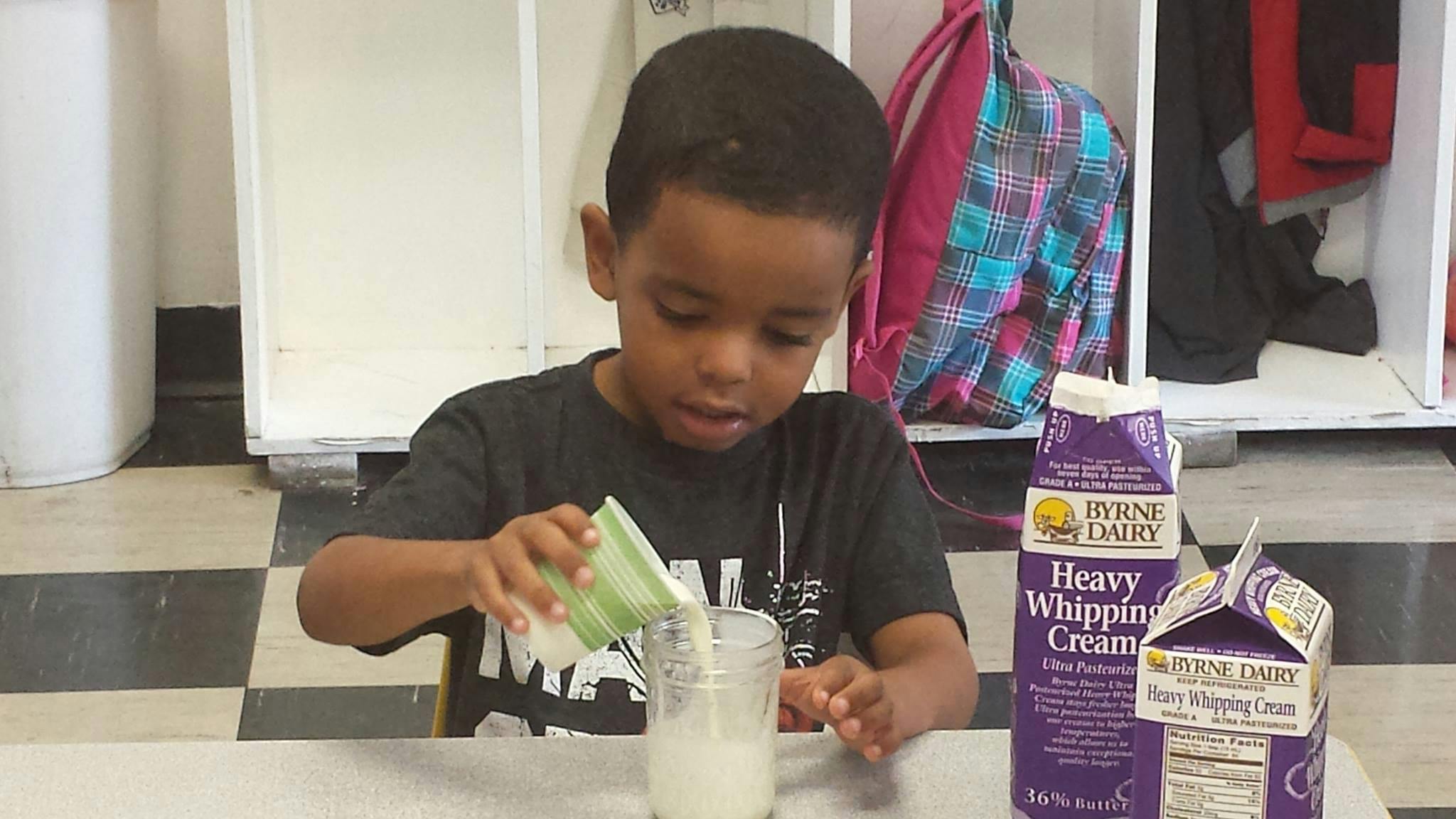 Child pouring liquid from a small container into a glass