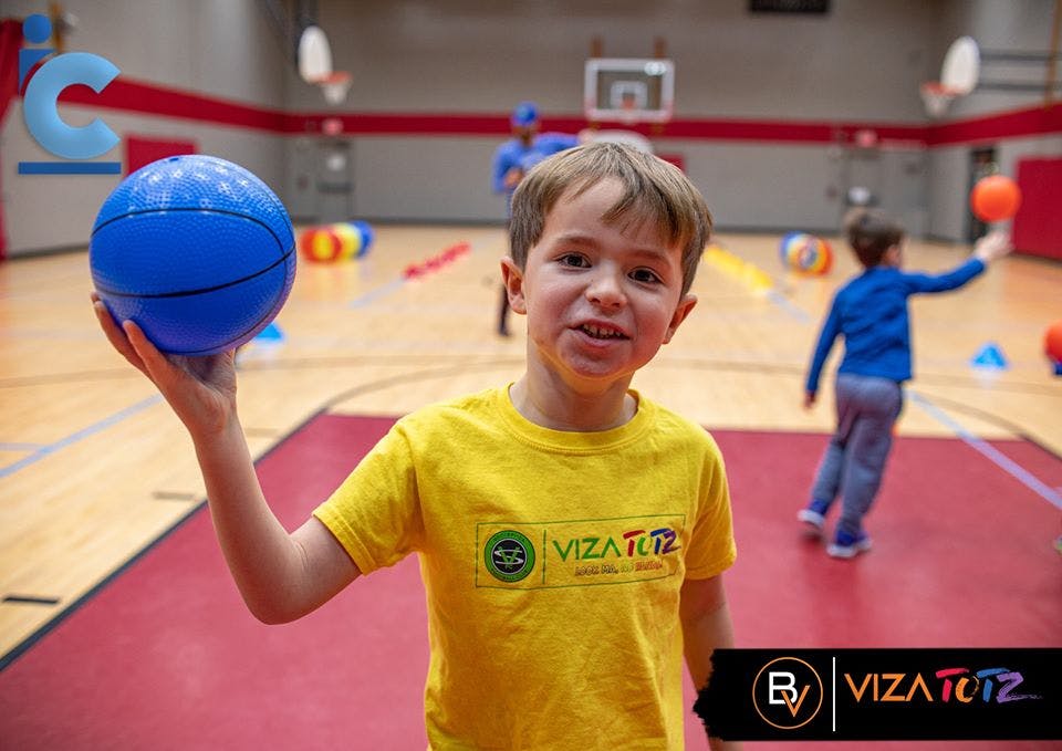 Child holding a blue basketball in a gym