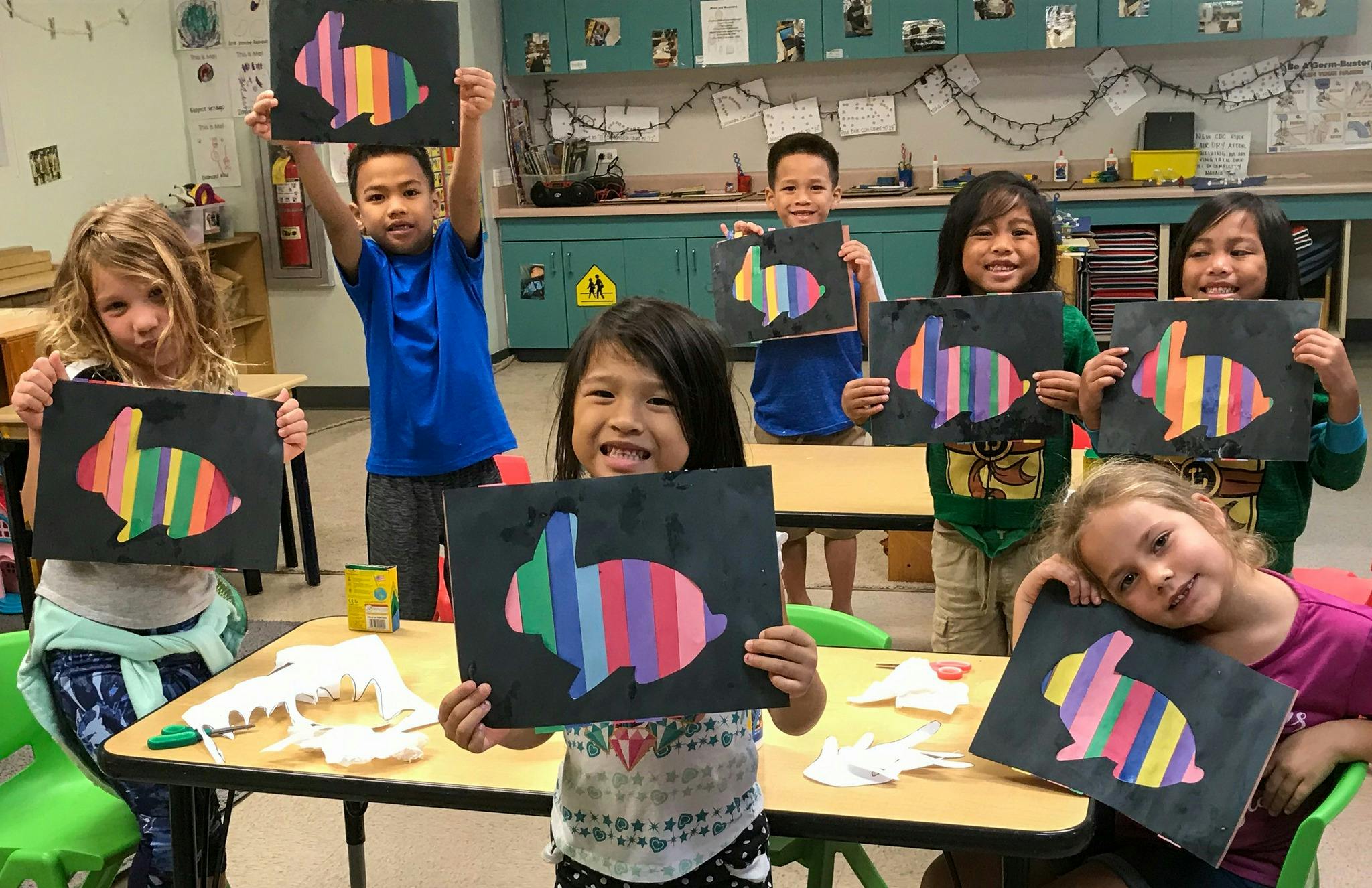 Children holding up artwork of colorful striped bunnies