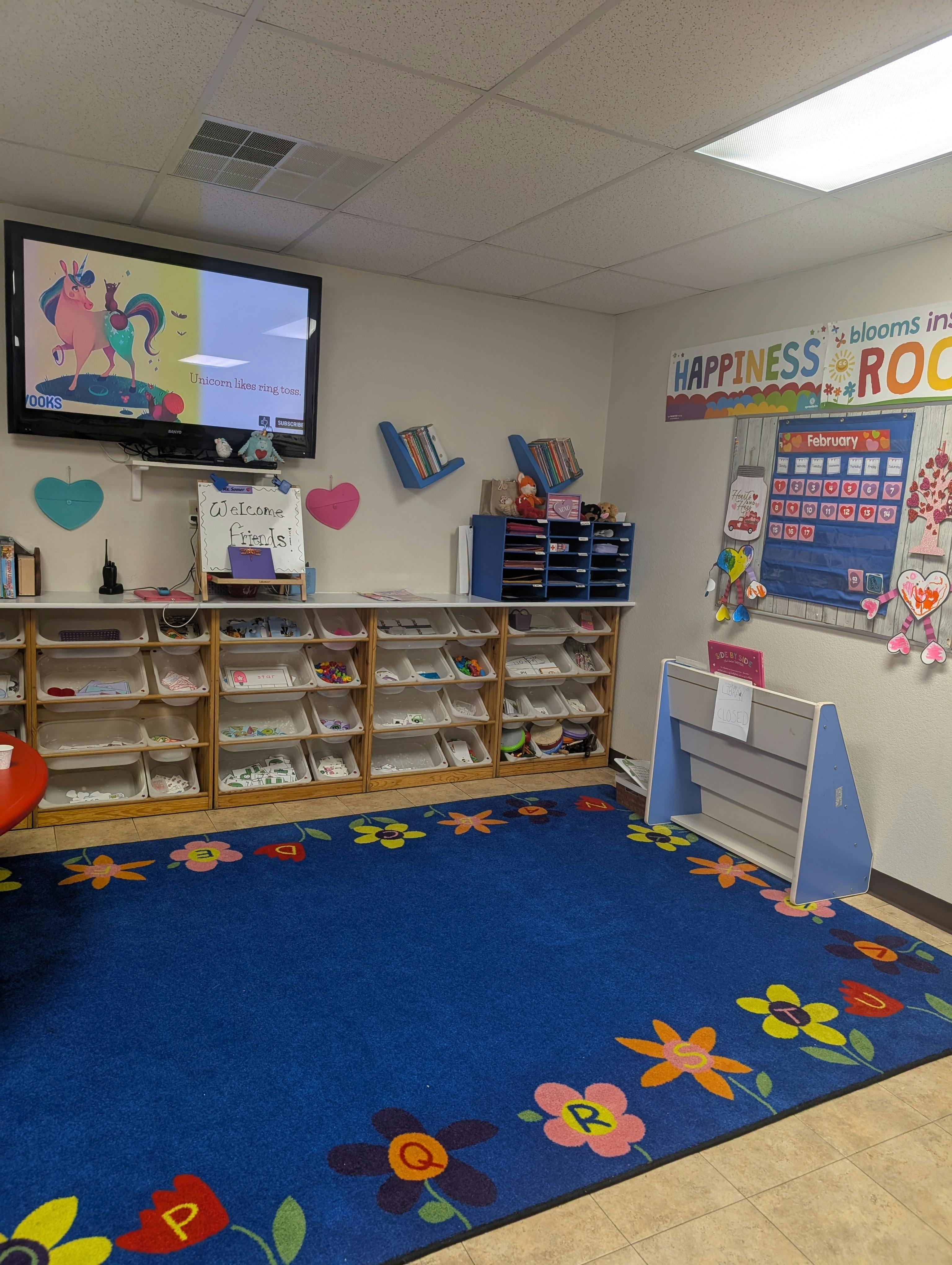 Classroom with a television displaying cartoon unicorns and storage shelves
