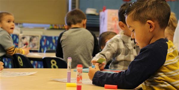 Child drawing at a table in a classroom