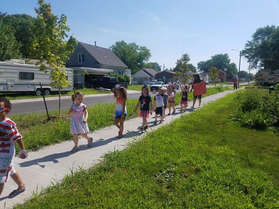 Children walking in a line on a sidewalk
