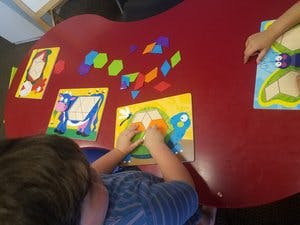 Child playing with a turtle puzzle on a red table