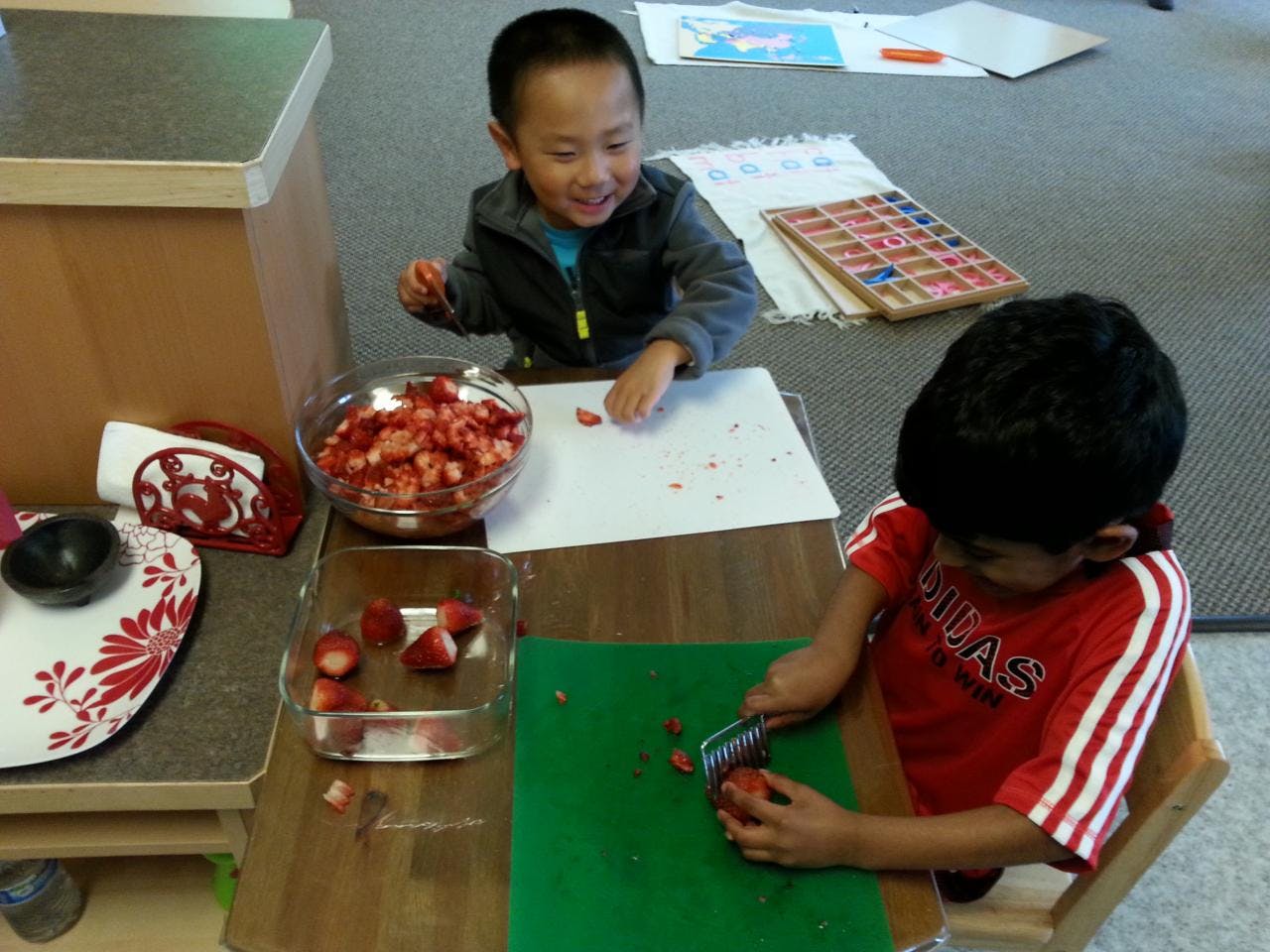Two children preparing strawberries at a table