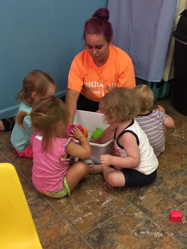 Adult and children playing with toys in a bin