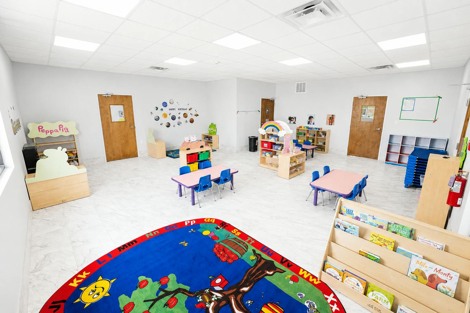 Empty preschool classroom with small tables and shelves for children