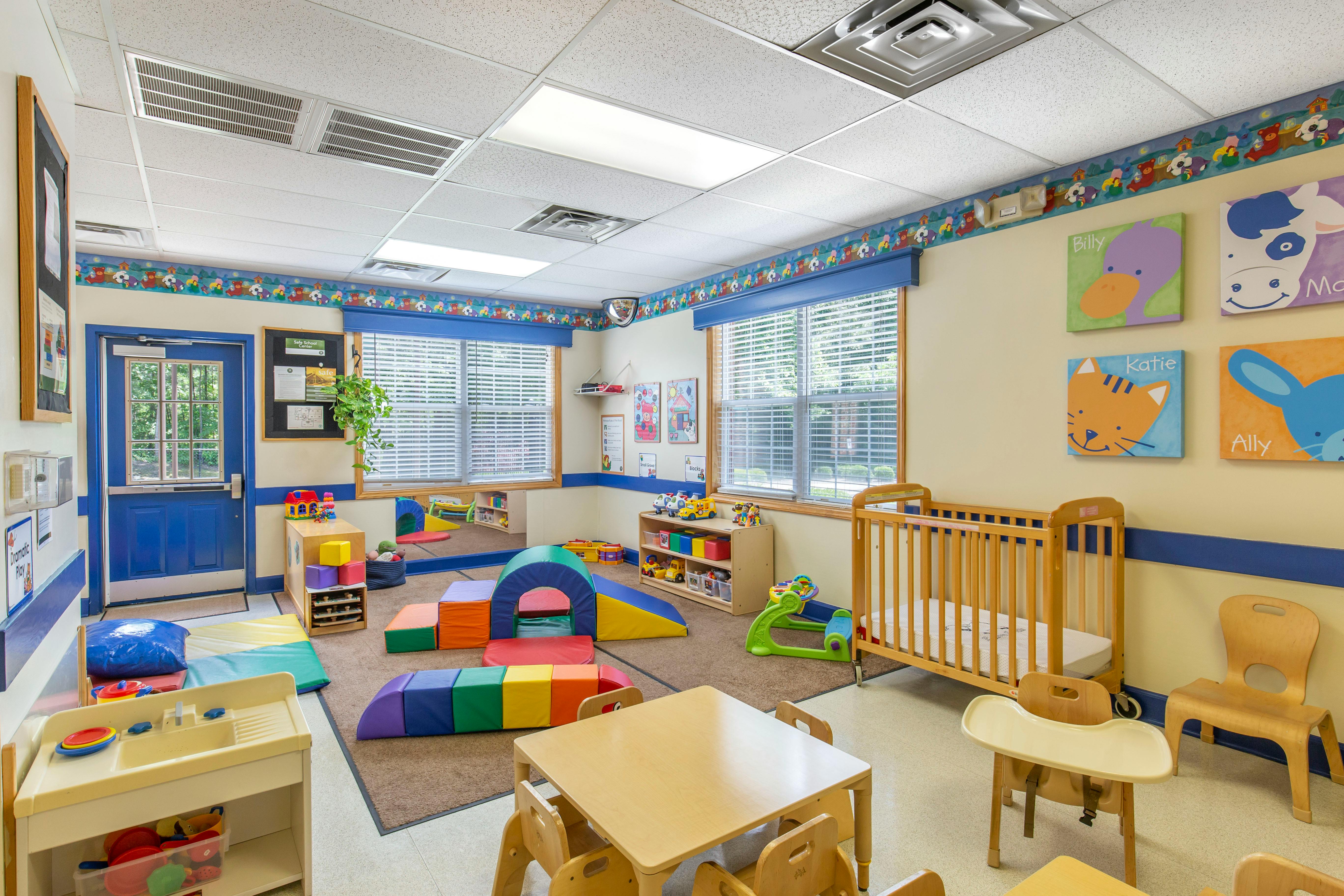A colorful daycare or preschool classroom with toys, small tables, and a crib