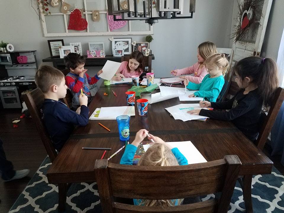 Children drawing and writing at a large table