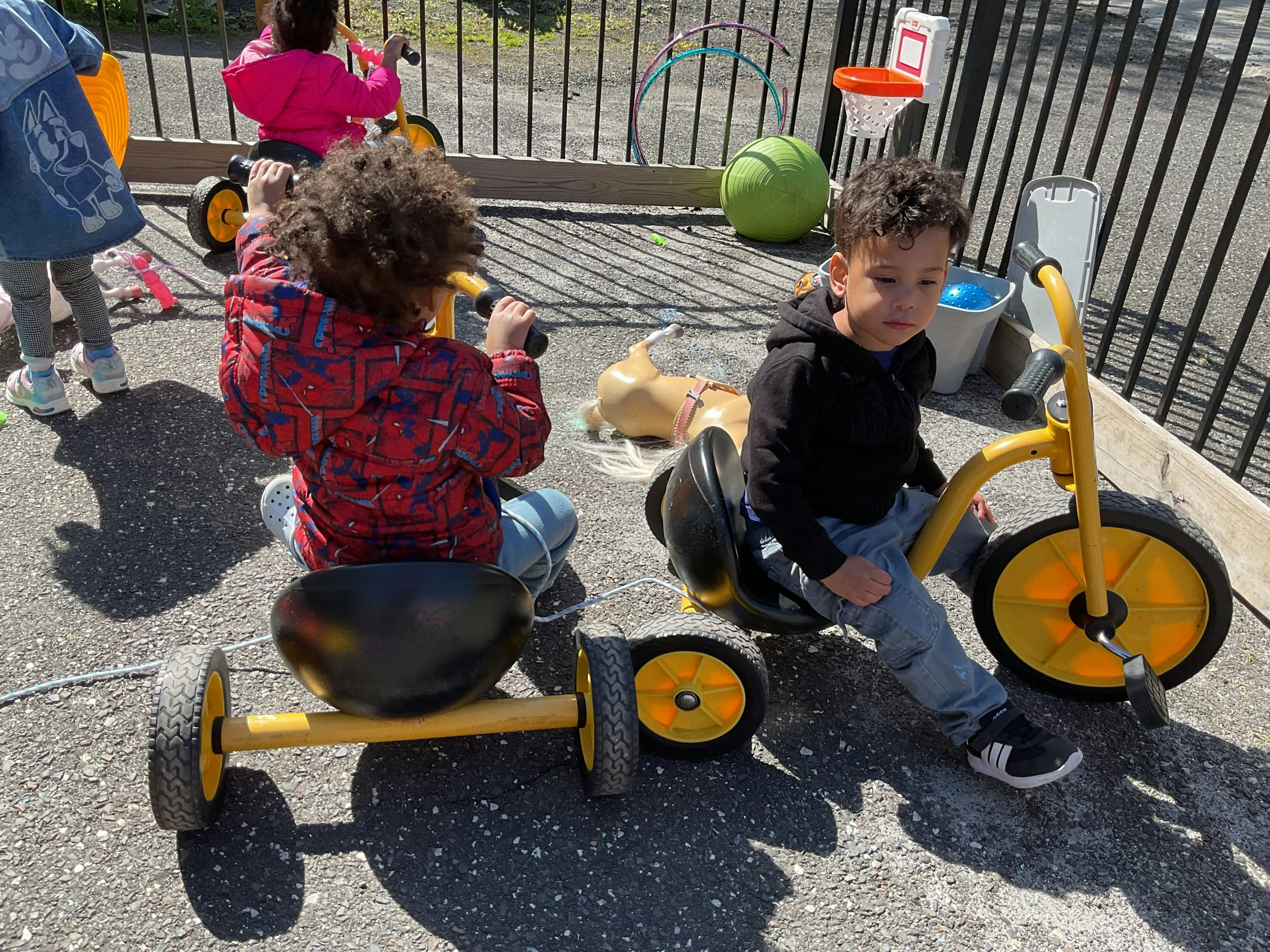 Children playing with tricycles and toys outdoors