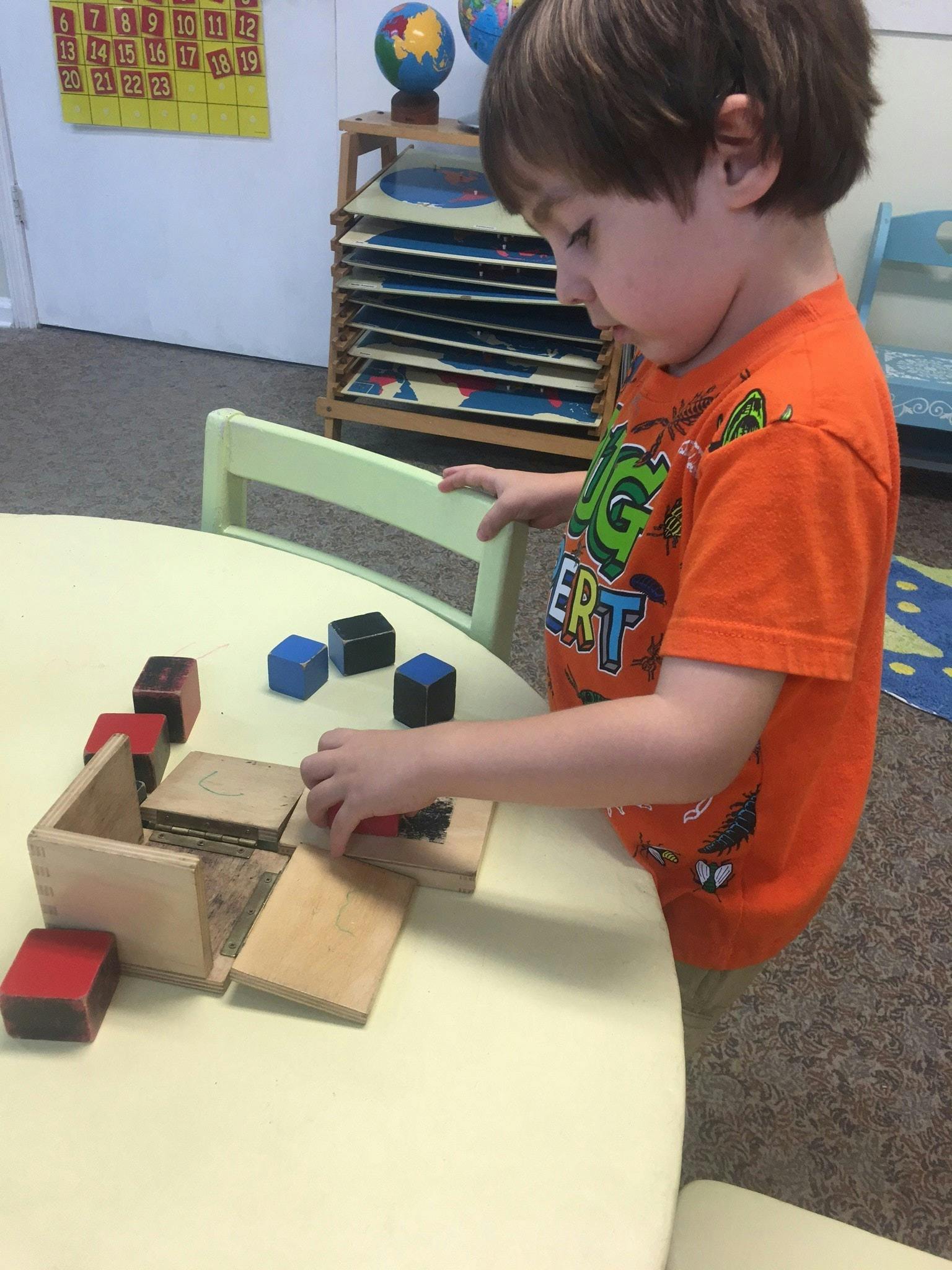 Child playing with wooden blocks and colored cubes at a table