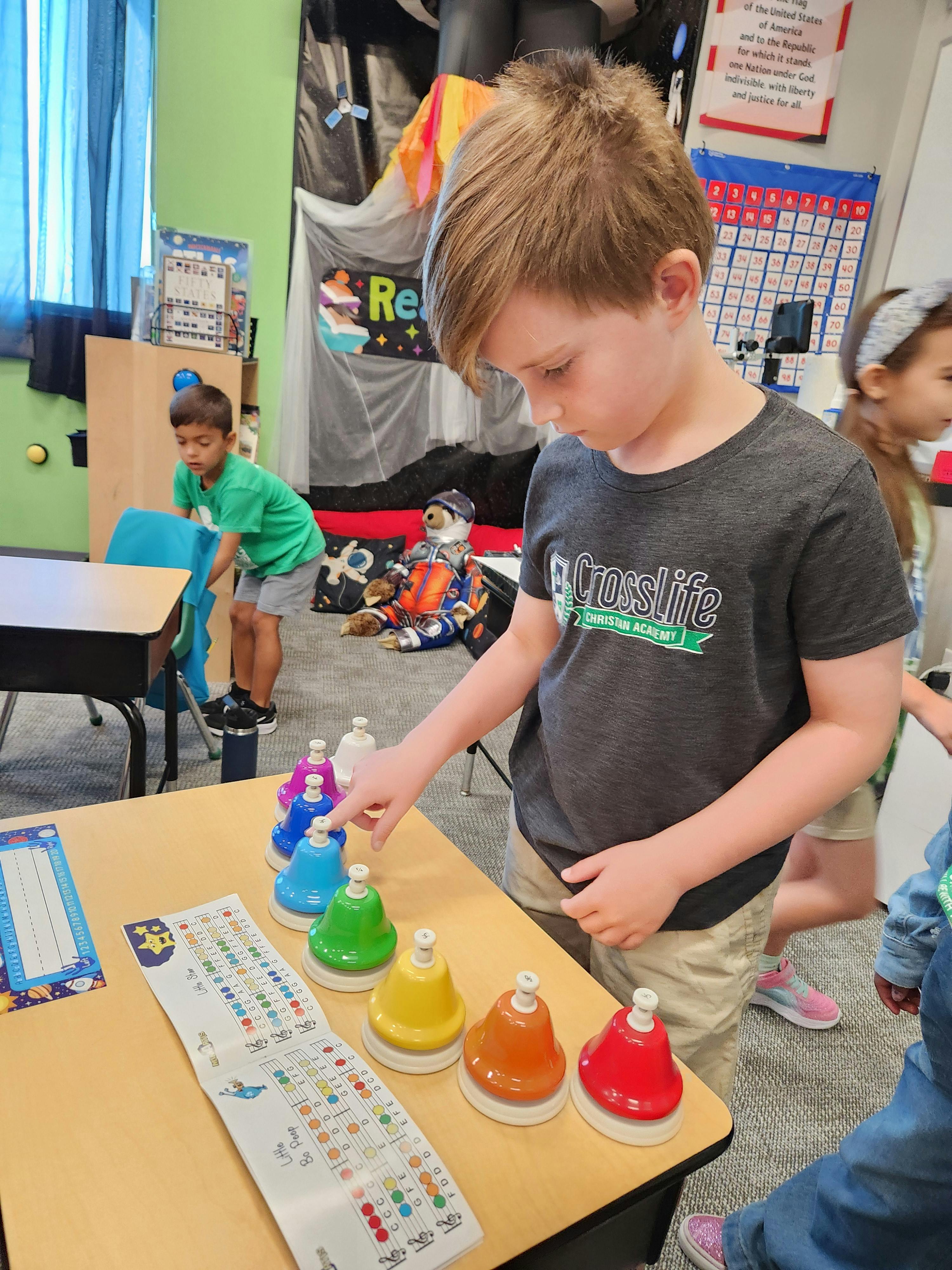 Child playing with colorful musical bells on a table