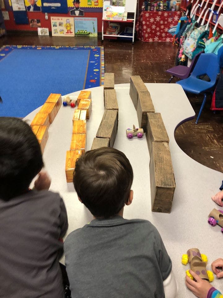 Children playing with toy cars and blocks on a table