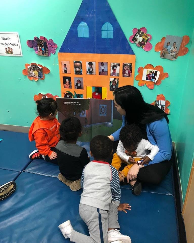 Adult reading a book to a group of children in a classroom